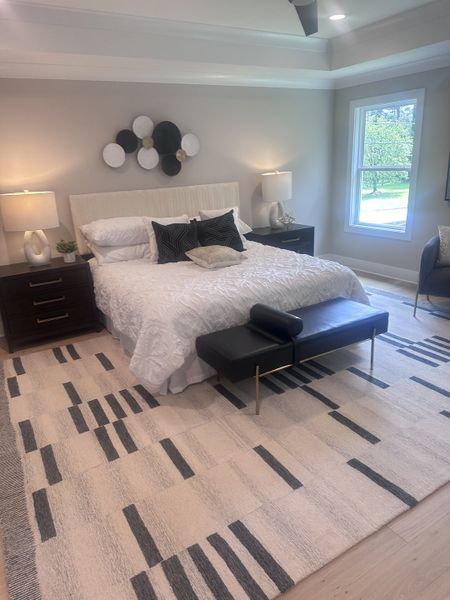 A cozy bedroom featuring a plush bed, modern decor, sleek nightstands, and a large window with a calming view. A cozy bedroom featuring a plush bed, modern decor, sleek nightstands, and a large window with a calming view.