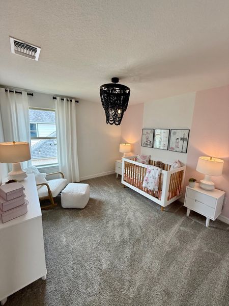 A cozy nursery featuring soft carpeting, a modern crib, and elegant lighting with soft, neutral decor.