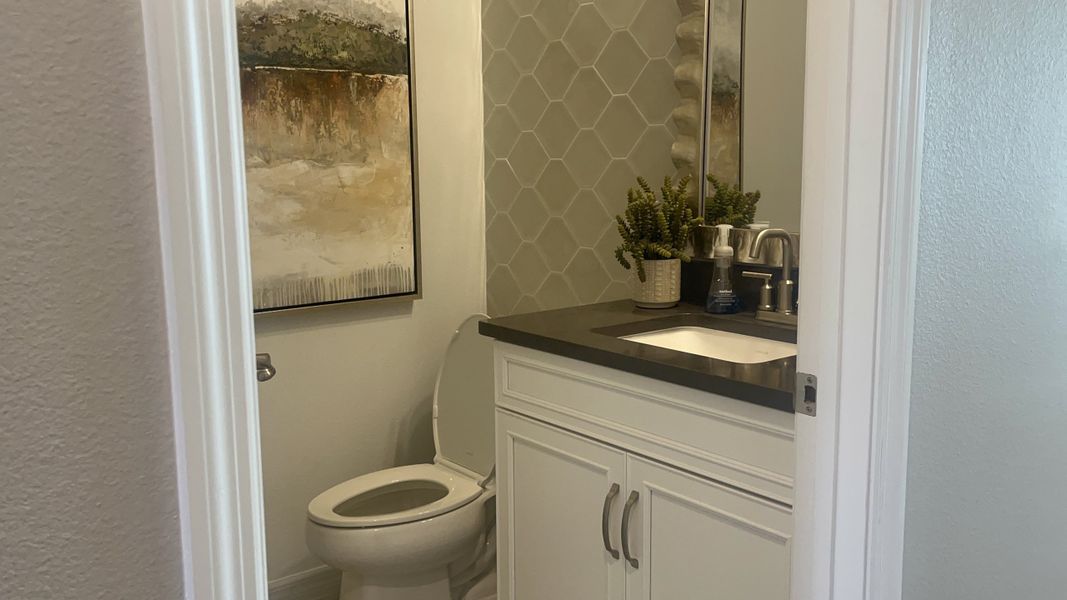 A modern bathroom with hexagonal tile, sleek vanity, and abstract art adding a touch of elegance.