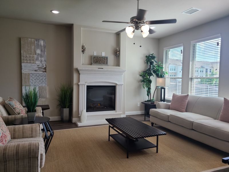 A cozy living room featuring a classic fireplace, modern art, and elegant seating with natural light and greenery. A cozy living room featuring a classic fireplace, modern art, and elegant seating with natural light and greenery.
