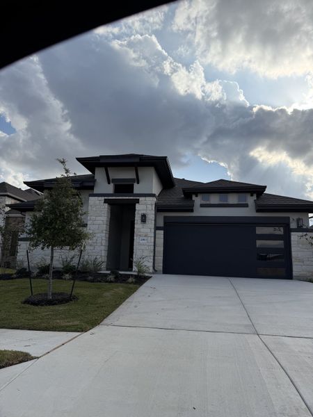 A modern stone home with a sleek design and manicured lawn in Carillon by Brightland Homes (Manor, TX). A modern stone home with a sleek design and manicured lawn in Carillon by Brightland Homes (Manor, TX).