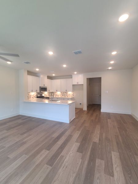An open-concept kitchen with sleek cabinetry, light wood floors, and recessed lighting.