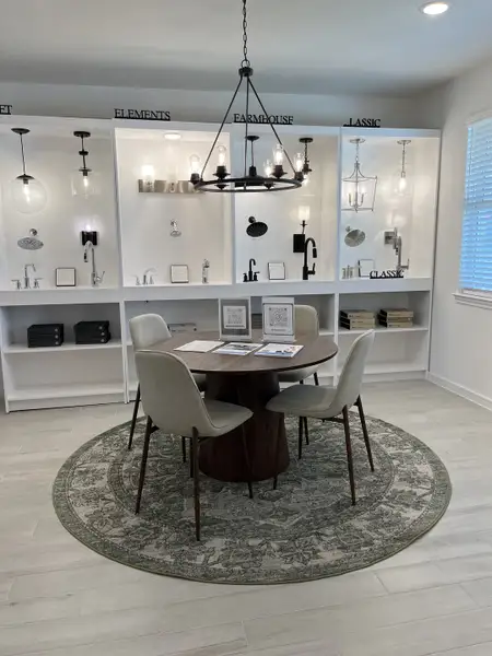 A chic showroom featuring elegant lighting displays, a round table with modern chairs, and a patterned rug. A chic showroom featuring elegant lighting displays, a round table with modern chairs, and a patterned rug.