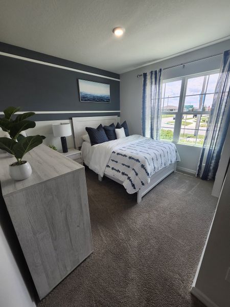 A cozy bedroom with modern navy accents, striped curtains, and abundant natural light.