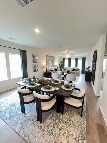 A modern dining area with a dark wood table, elegant seating, and natural light flowing into an open living room.