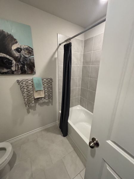 A cozy bathroom featuring a tiled tub, soft gray accents, and vibrant artwork for a modern touch.
