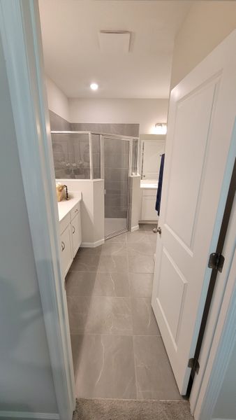 A sleek bathroom with gray tile flooring, glass shower enclosure, and a modern vanity setup. A sleek bathroom with gray tile flooring, glass shower enclosure, and a modern vanity setup.