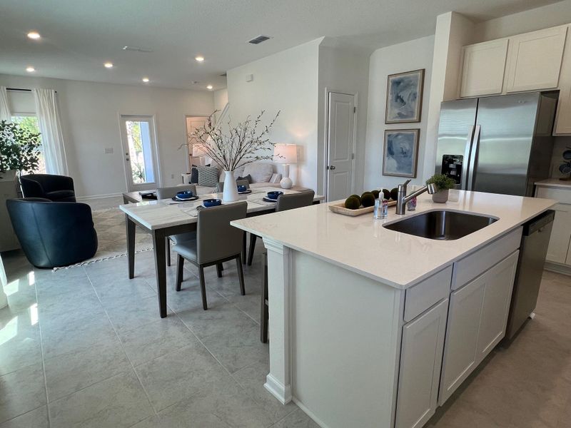 An open-concept living area featuring a sleek kitchen island, elegant dining space, and cozy seating in neutral tones.