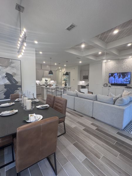 A modern living and dining area with sleek furnishings, neutral tones, and stylish lighting fixtures.