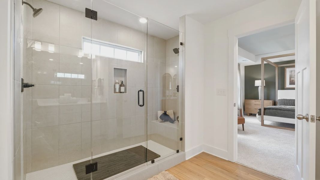 Luxury primary bathroom with tiled walk-in Roman shower with bench seat at Fox Hollow by DRB Homes in Spartanburg, SC