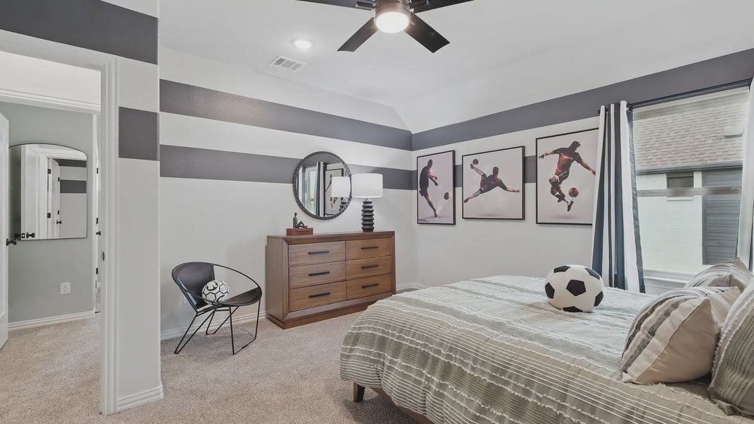 Sophisticated bedroom with striped walls, fine wood dresser, and chic sports accents in Westridge. Luxurious yet playful.