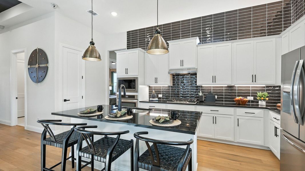 Sleek white cabinetry and glossy black tiles define this exquisite kitchen in Green Oaks Preserve. Sleek white cabinetry and glossy black tiles define this exquisite kitchen in Green Oaks Preserve.