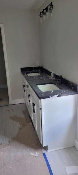 A sleek double vanity with a black countertop, modern fixtures, and soft lighting illuminates this stylish bathroom space.