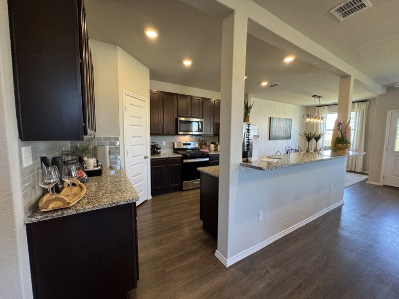 A modern kitchen with dark wood cabinets, granite countertops, and stainless steel appliances.