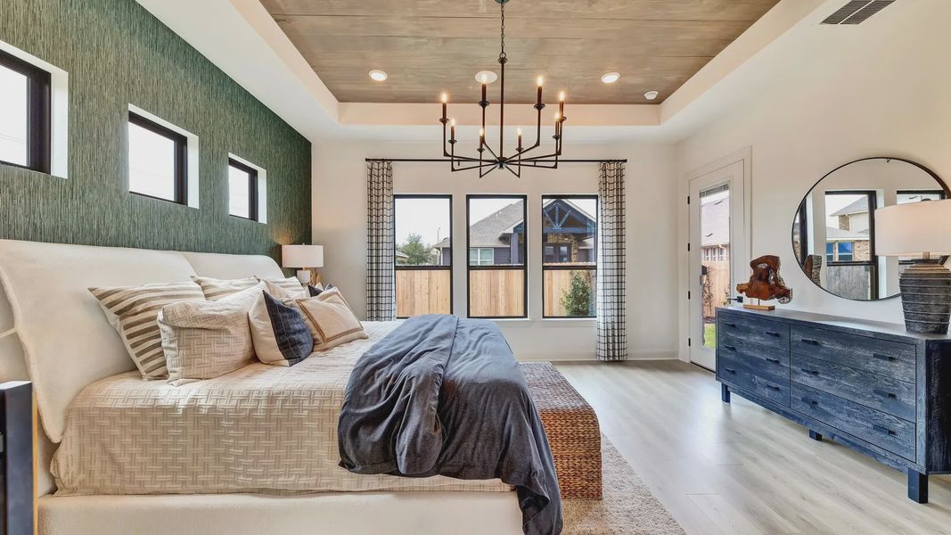 Sophisticated bedroom features textured accent wall, chic chandelier, and premium wood flooring. Hawkes Landing locale.