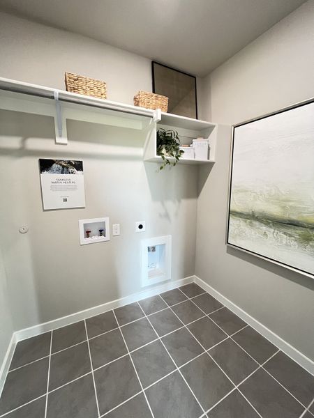 A modern laundry room with sleek gray tiles, open shelving, and contemporary artwork. A modern laundry room with sleek gray tiles, open shelving, and contemporary artwork.