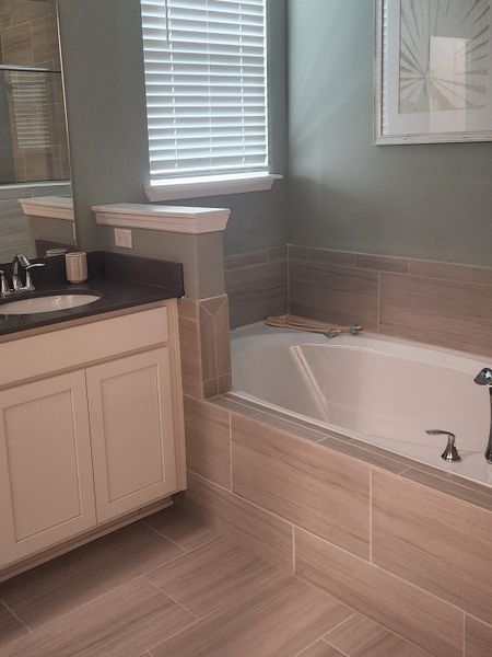 A cozy bathroom featuring a tiled bathtub, sleek vanity, and a modern framed artwork, creating a serene retreat. A cozy bathroom featuring a tiled bathtub, sleek vanity, and a modern framed artwork, creating a serene retreat.