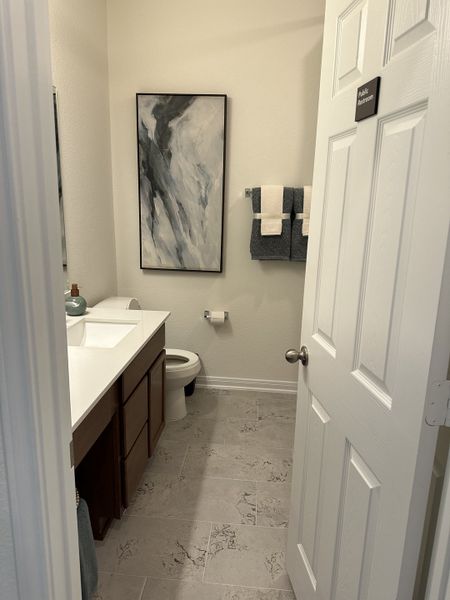 A contemporary bathroom features abstract art, sleek vanity, and tiled floors.