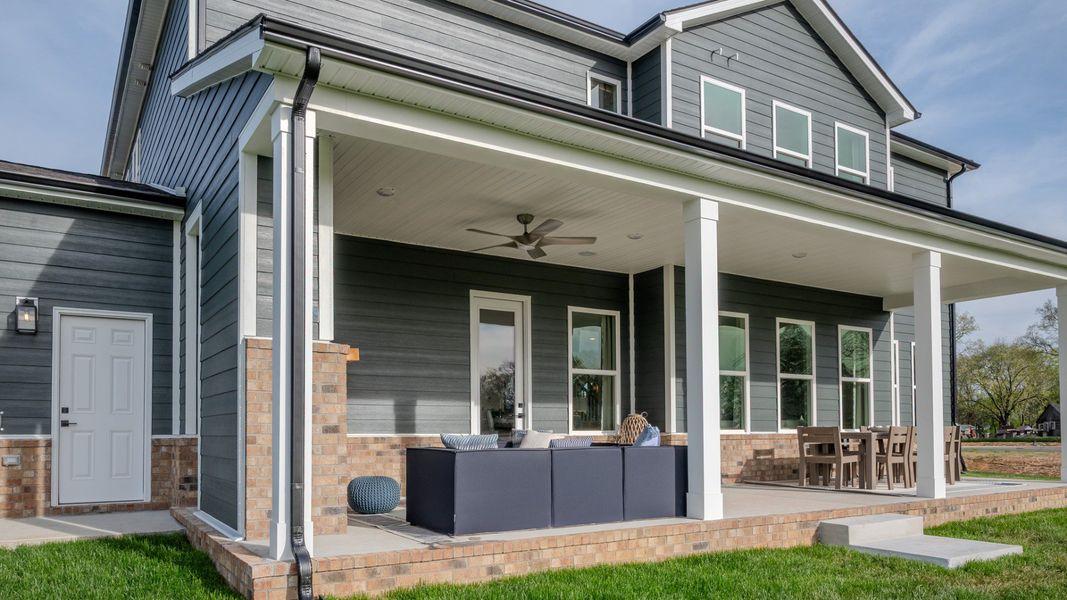 Covered outdoor seating area with fireplace and mantel, outdoor sectional, and outdoor dining area