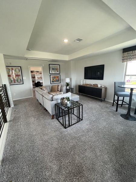 A cozy living room with plush carpet, modern decor, a sectional sofa, and wall-mounted TV offering a relaxed ambiance. A cozy living room with plush carpet, modern decor, a sectional sofa, and wall-mounted TV offering a relaxed ambiance.