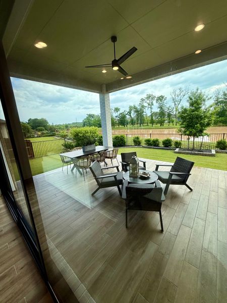 A serene covered patio with wicker chairs, a dining set, and garden views, perfect for outdoor lounging and dining.