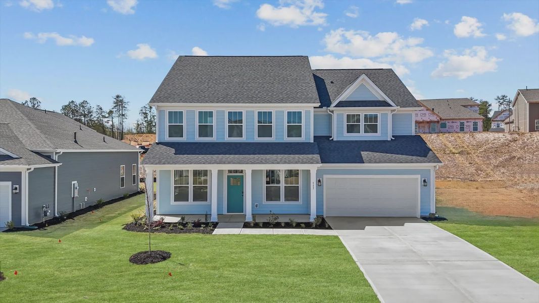 Bright blue home with plentiful windows and long driveway in Woodruff, SC at Pinebrook by DRB Homes Bright blue home with plentiful windows and long driveway in Woodruff, SC at Pinebrook by DRB Homes