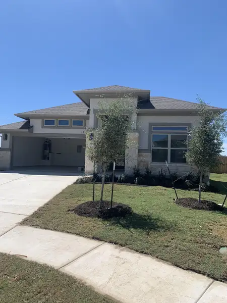 A modern stone-accented home with fresh landscaping in Carillon by Brightland Homes (Manor, TX). A modern stone-accented home with fresh landscaping in Carillon by Brightland Homes (Manor, TX).