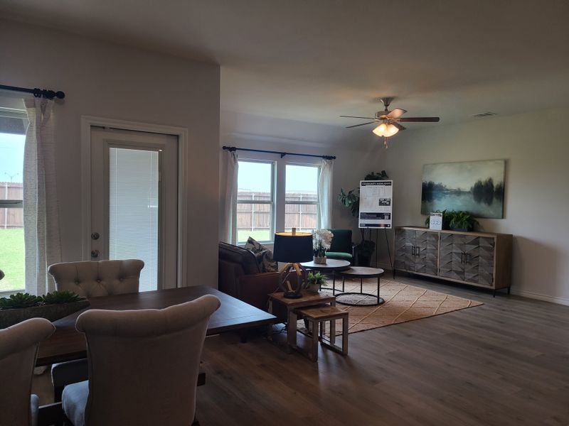 An inviting open-plan living area with elegant furniture, warm lighting, and large windows overlooking a green lawn.