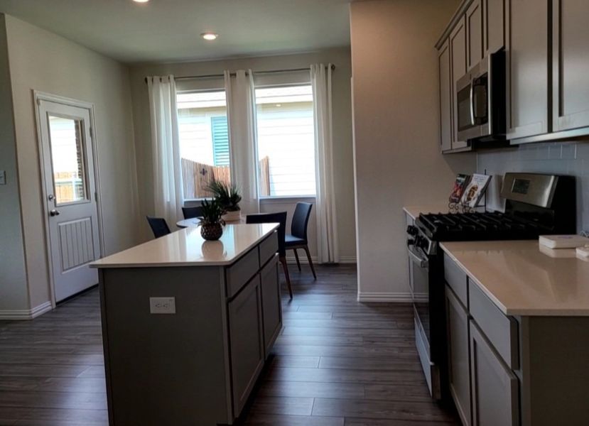 A modern kitchen with sleek cabinetry, stainless steel appliances, and wood-style flooring.