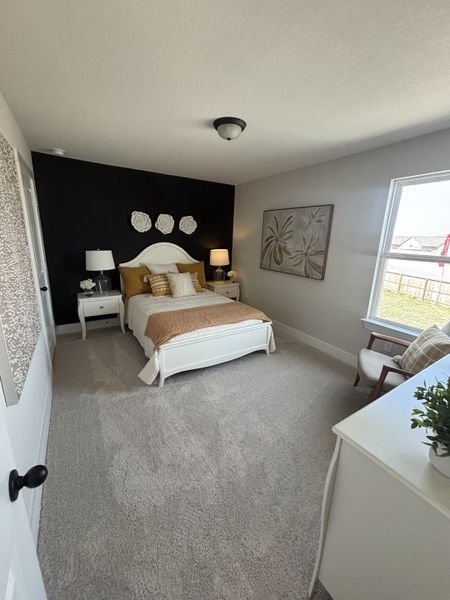 A comfortable and beautifully styled bedroom with a black accent wall, a white bed frame, and mustard-colored bedding. A comfortable and beautifully styled bedroom with a black accent wall, a white bed frame, and mustard-colored bedding.