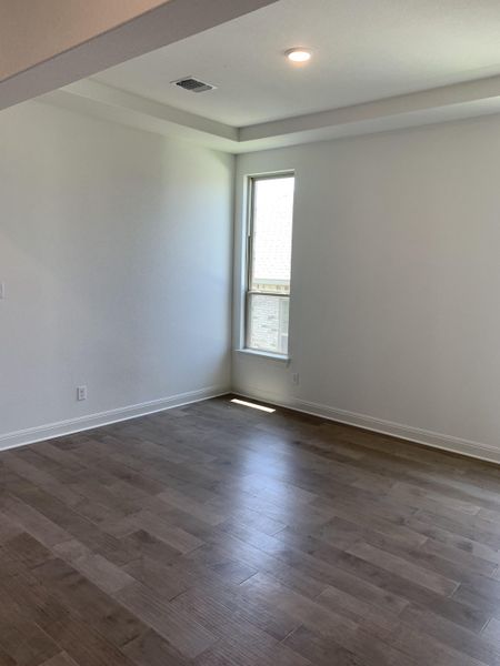 Bright room with wood flooring, a recessed ceiling, and natural light from a tall window, creating an inviting atmosphere. Bright room with wood flooring, a recessed ceiling, and natural light from a tall window, creating an inviting atmosphere.