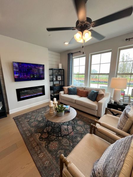 A cozy living room featuring a fireplace, chic decor, and ample natural light, with a plush couch and stylish coffee table.