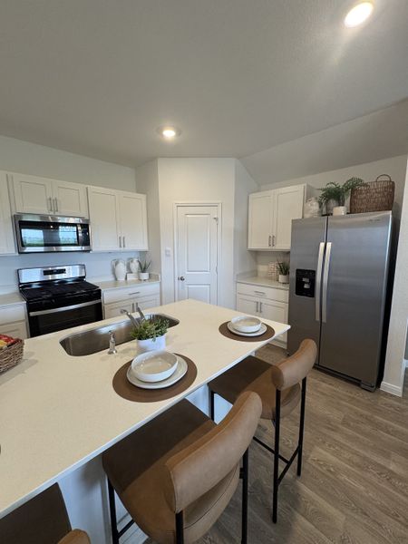 A modern kitchen with white cabinetry, sleek appliances, and a central island with seating. A modern kitchen with white cabinetry, sleek appliances, and a central island with seating.