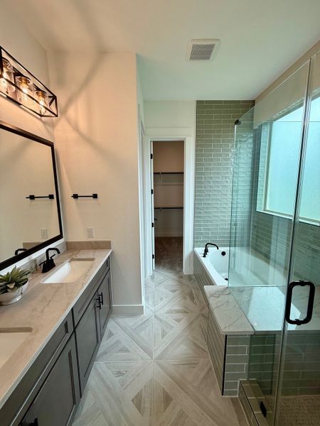 A sleek bathroom featuring a dual-sink vanity, glass-enclosed shower, and subway tile accents.