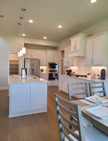 A modern kitchen with sleek white cabinetry, an island, stainless steel appliances, and elegant pendant lighting. A modern kitchen with sleek white cabinetry, an island, stainless steel appliances, and elegant pendant lighting.