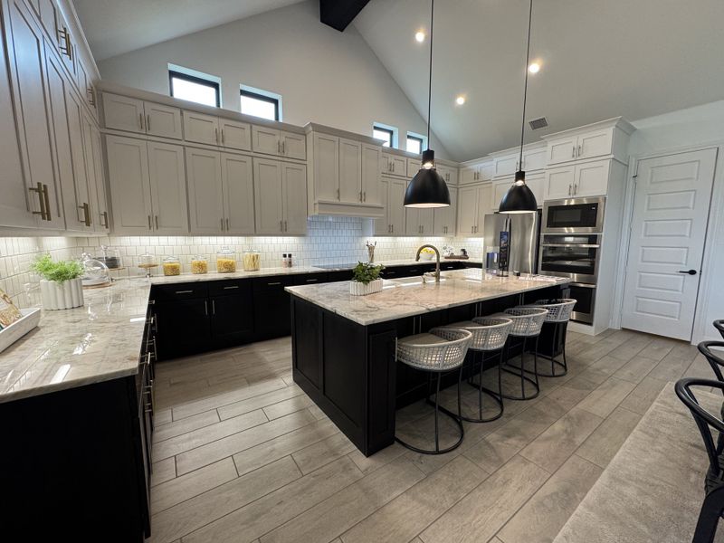 A spacious modern kitchen with marble countertops, black and white cabinetry, and elegant pendant lighting. A spacious modern kitchen with marble countertops, black and white cabinetry, and elegant pendant lighting.