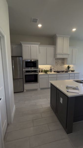 A modern kitchen with sleek white cabinets, stainless steel appliances, and an elegant island for culinary inspiration.