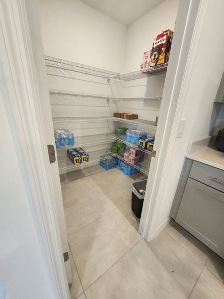 A spacious pantry with sleek wire shelving, tiled flooring, and ample storage space.