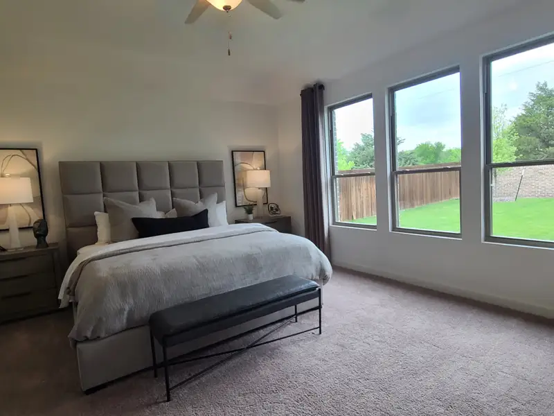A spacious bedroom featuring a plush bed, elegant decor, and large windows with a view of a lush green yard. A spacious bedroom featuring a plush bed, elegant decor, and large windows with a view of a lush green yard.
