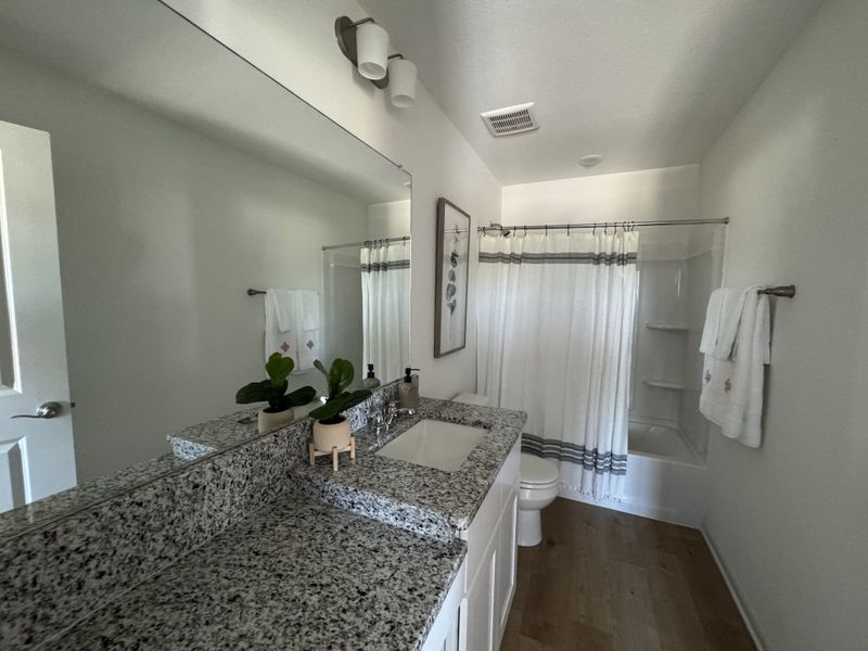 A modern bathroom featuring a granite countertop, stylish lighting, and a shower with a white curtain for an elegant touch. A modern bathroom featuring a granite countertop, stylish lighting, and a shower with a white curtain for an elegant touch.