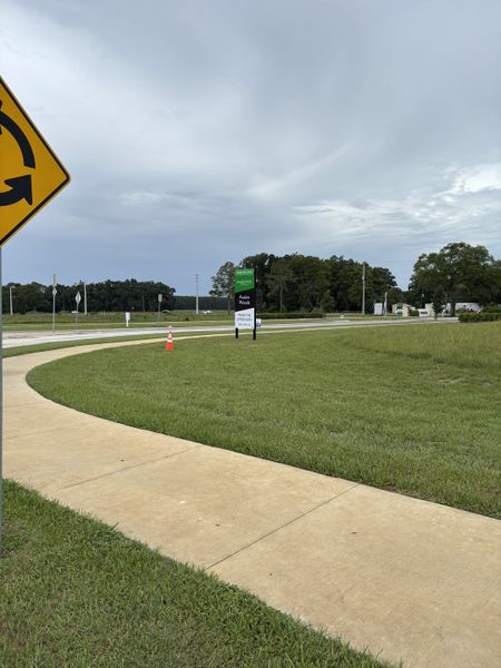 A welcoming entry to Avalon Woods by D.R. Horton, featuring landscaped paths and open green spaces in Newberry, FL.
