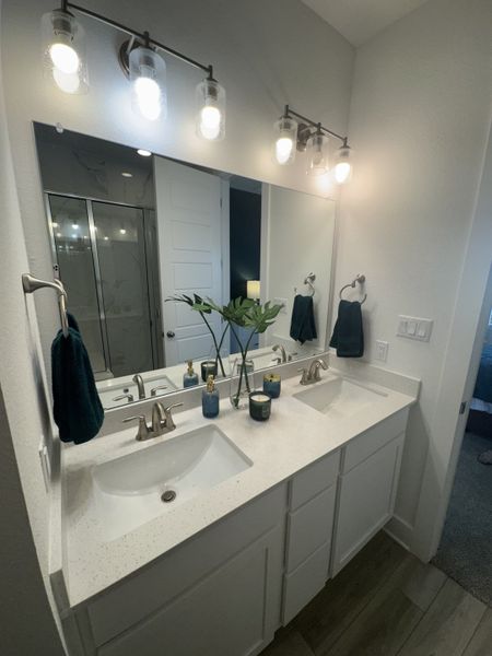 A modern bathroom featuring a dual sink vanity, sleek lighting, and chic decor accents.