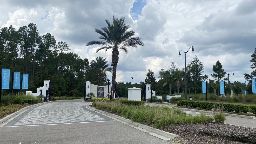 A welcoming entrance with palm trees and landscaping at Stillwater | Active Adult 55+: Stillwater - Villas by Lennar (St. Johns, FL).