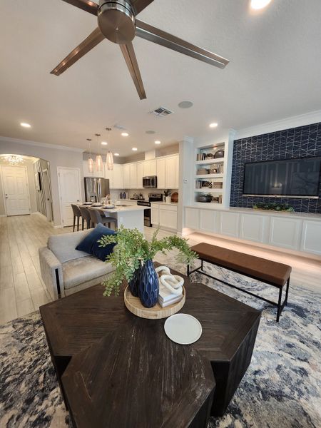 Modern living space with open layout, sleek kitchen, geometric wall design, and cozy seating.