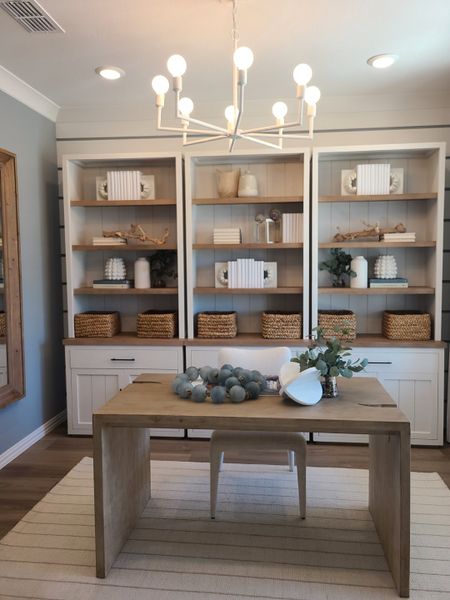 A cozy home office with built-in shelving, a sleek wooden desk, and a modern chandelier.