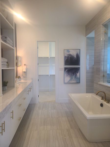 A luxurious bathroom with a marble vanity, freestanding tub, and elegant artwork creates a serene ambiance.