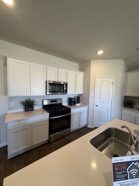A modern kitchen with sleek white cabinets, stainless steel appliances, and a spacious countertop.