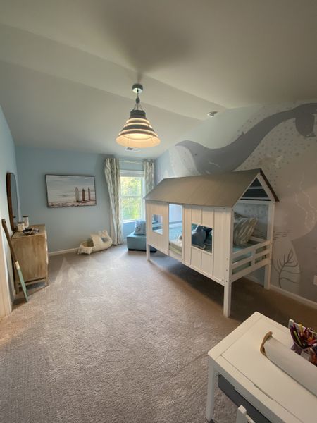 A cozy children's room with an ocean-themed mural, house-shaped bed, and soft lighting create a playful atmosphere.
