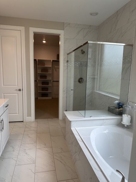 A luxurious bathroom with marble-style tiles, a walk-in shower, and a sleek bathtub exudes sophistication and comfort. A luxurious bathroom with marble-style tiles, a walk-in shower, and a sleek bathtub exudes sophistication and comfort.