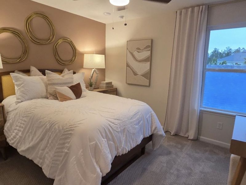 A cozy bedroom featuring a plush bed with layered pillows, ambient lighting, and artistic wall decor for a serene ambiance.